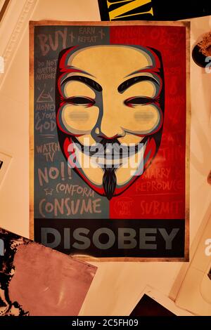 Désobéir. Une affiche sur un plafond, Madrid, jouant sur obéir, Guy Fawkes masque, Anonymous hackers, V pour vendetta, montrant des règles typiques à suivre ou à briser Banque D'Images