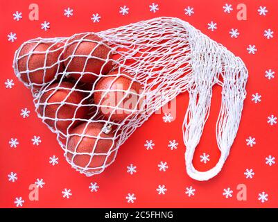 Sac écologique en coton à fil blanc avec cinq boules d'arbre sur fond rouge et flocons de neige blancs épars. Simple étapage de vacances. Ecologie zéro wast Banque D'Images