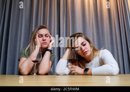 Une femme console une triste amie dépressive qui a besoin d'aide. Dépression avec alcool concept. Bouleversé jeune fille avec visage malheureux tenant un verre de vin lo Banque D'Images