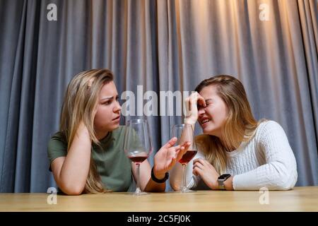 Une femme console une triste amie dépressive qui a besoin d'aide. Dépression avec alcool concept. Bouleversé jeune fille avec visage malheureux tenant un verre de vin lo Banque D'Images