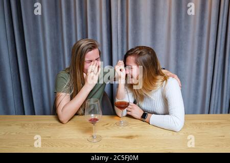 Une femme console une triste amie dépressive qui a besoin d'aide. Dépression avec alcool concept. Bouleversé jeune fille avec visage malheureux tenant un verre de vin lo Banque D'Images