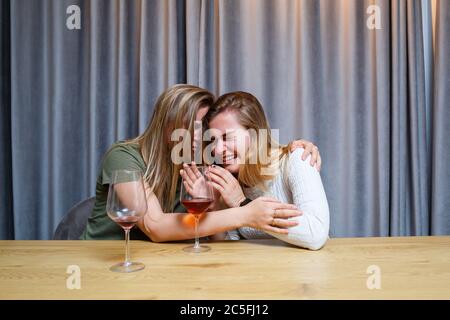 Une femme console une triste amie dépressive qui a besoin d'aide. Dépression avec alcool concept. Bouleversé jeune fille avec visage malheureux tenant un verre de vin lo Banque D'Images