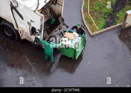 enlèvement des ordures dans un quartier résidentiel, des hommes de déchets chargeant des ordures ménagères dans un camion à ordures Banque D'Images