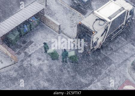 Camion à ordures et deux travailleurs dans la tempête de neige, vue de dessus Banque D'Images