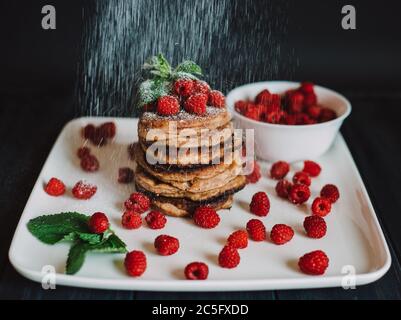 Crêpes au chocolat avec framboises fraîches et menthe sur fond noir Banque D'Images
