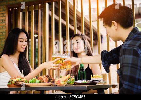 Les amis asiatiques Teeneger se régalent de verres tout en dégustant un dîner dans un restaurant. Banque D'Images