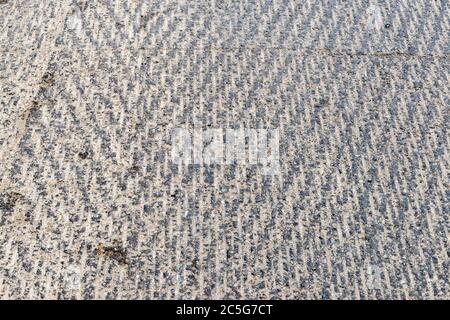 Surface d'une route qui a été raclée en vue d'un nouveau pavage. La couche supérieure a été supprimée, laissant un motif rugueux. Banque D'Images