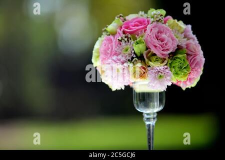 Un grand bouquet de fleurs et coloré dans un vase en verre transparent sur fond vert flou, utilisé dans les cérémonies de mariage. Banque D'Images