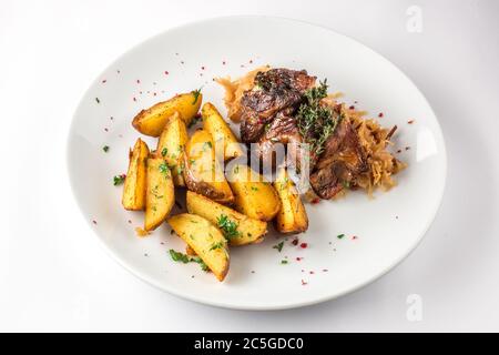 Porte-jarret de porc avec pommes de terre et chou sur une assiette blanche. Mise au point sélective. Banque D'Images