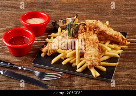 Délicieux mets dorés filets de poisson frits et frites, servis sur un plan de travail en bois, vue d'en haut. Banque D'Images