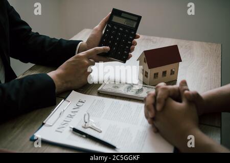 Les agents calculent le taux de paiement du prêt ou le montant des primes d'assurance pour les clients qui viennent contacter l'achat d'une nouvelle maison à l'extérieur Banque D'Images