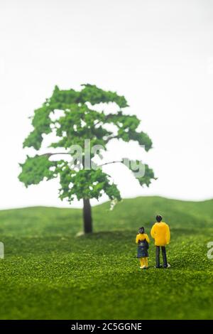 Concept de nature d'amour : figurines de couple miniature devant un arbre Banque D'Images
