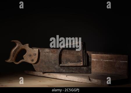 Boîte à onglets en bois antique et en fonte avec scie à dos en tenon avec capuchon de renfort, éclairage directionnel et espace de copie. Banque D'Images