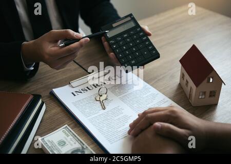 Les agents calculent le taux de paiement du prêt ou le montant des primes d'assurance pour les clients qui viennent contacter l'achat d'une nouvelle maison à l'extérieur Banque D'Images