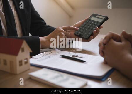Les agents calculent le taux de paiement du prêt ou le montant des primes d'assurance pour les clients qui viennent contacter l'achat d'une nouvelle maison à l'extérieur Banque D'Images