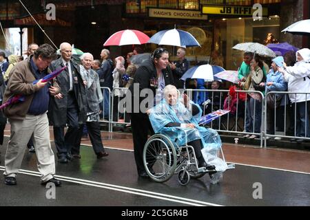 Un vétéran de la guerre en fauteuil roulant se fait passer devant la foule en prenant part à la parade annuelle de la journée de l'ANZAC sur George Street, Sydney. Banque D'Images