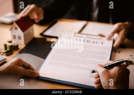 Le personnel de vente de biens immobiliers soumet des documents de contrat d'hypothèque foncière aux acheteurs de maison pour signature. Banque D'Images