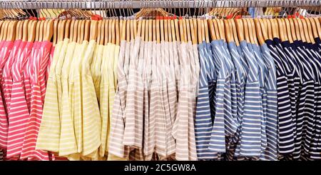 T-shirts à rayures multicolores sur les cintres dans le magasin de vêtements Banque D'Images