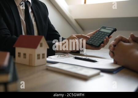 Les agents calculent le taux de paiement du prêt ou le montant des primes d'assurance pour les clients qui viennent contacter l'achat d'une nouvelle maison à l'extérieur Banque D'Images