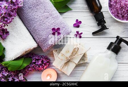 Cadre spa avec fleurs de lilas. Sel de mer dans un bol, bouteilles d'huile aromatique et bougies sur fond de bois. Banque D'Images