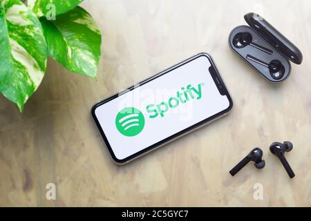 Bangkok, Thaïlande - 3 juillet 2020 : Apple iPhone 11 avec logo Spotify sur l'écran, casque bluetooth avec étui, plante verte sur table de travail backgrou Banque D'Images