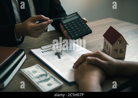 Les agents calculent le taux de paiement du prêt ou le montant des primes d'assurance pour les clients qui viennent contacter l'achat d'une nouvelle maison à l'extérieur Banque D'Images