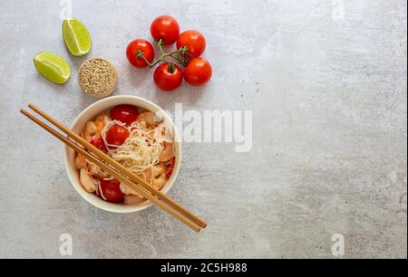 Nouilles diététiques shirataki konjak avec crevettes et tomates dans un bol avec baguettes. Banque D'Images