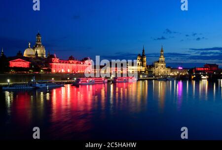 22 juin 2020, Saxe, Dresde: Le bâtiment Lipsius (l), l'Académie des Arts, les Salongships de la Sächsische Dampfschiffahrt et l'Opéra Semper (r) sont illuminés en rouge dans la soirée, derrière lesquels se trouvent la Frauenkirche (l-r), la St?ndehaus, le Hausmannsturm et la Hofkirche. La Saxe participe à la campagne nationale ÇNight de lightÈ. Dans la nuit du 23 juin, les lieux et certains bâtiments de l'Allemagne seront éclairés en rouge pour attirer l'attention sur la situation dramatique provoquée par la pandémie de couronne dans l'industrie de l'événement. Photo: Robert Michael/dpa-Zentr Banque D'Images