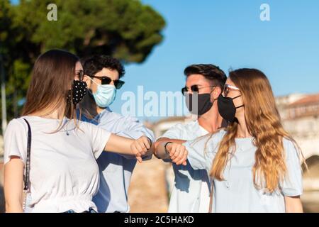 les amis sont en santé avec des coudes - quatre jeunes disent bonjour à l'époque du coronavirus Banque D'Images