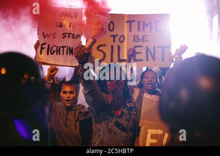 Les manifestants manifestent la nuit avec des bombes à fumée devant la police. Manifestation anti-gouvernementale par un groupe de militants sociaux. Banque D'Images