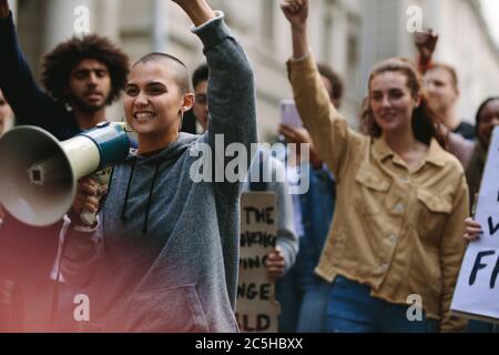 Jeune femme rebelle au mégaphone lors de manifestations de rue. Une femme protestante hurle au-dessus d'une corne de taureau alors qu'elle participe à une démonstration de rue. Banque D'Images