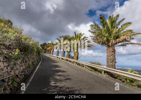 Vue panoramique sur la route asphaltée sur la côte de l'île entourant les collines et de voir en arrière-plan l'île de Gran Canary Banque D'Images