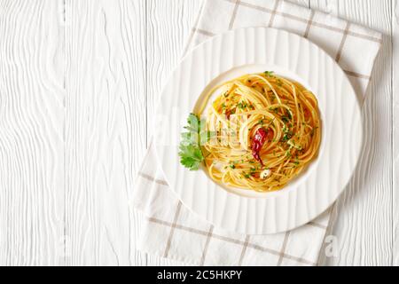 Spaghetti Alla colatura di alici, spaghetti à la sauce anchois, piment, ail et persil sur une assiette blanche sur une table blanche en bois, horizonta Banque D'Images