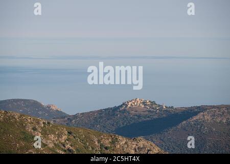 Lumière du matin sur le village de Sant'Antonino, au sommet d'une colline, au milieu d'une mer Méditerranée calme et d'un ciel bleu Banque D'Images