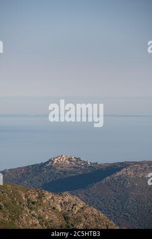 Lumière du matin sur le village de Sant'Antonino, au sommet d'une colline, au milieu d'une mer Méditerranée calme et d'un ciel bleu Banque D'Images