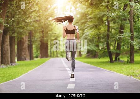Motivation sportive. Vue arrière du jogging Athletic Girl sur la piste du parc Banque D'Images