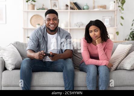 Date de l'alésage. Excité Black Guy jouant des jeux vidéo et ignorant petite amie à côté de lui Banque D'Images