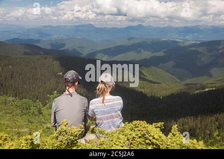 Deux touristes admirent la vallée de la montagne. Vue depuis le sommet de Neniska Mala. Carpates, MarMarmaris Mountains Banque D'Images