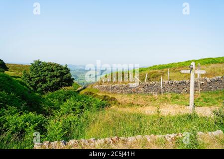 Un panneau en bois vieilli indique le chemin vers Baslow Edge et Curbar Edge par un matin d'été brumeux dans le district de Derbyshire Peak. Banque D'Images