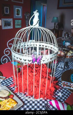 Thé coloré avec table mise en place de décorations de fantaisie de chapeaux, théières et cage d'oiseau ornemental Banque D'Images