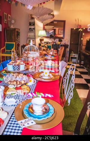 Thé coloré avec table, tasses à thé et soucoupes de fantaisie, avec des aliments sucrés et salés sur des plateaux Banque D'Images