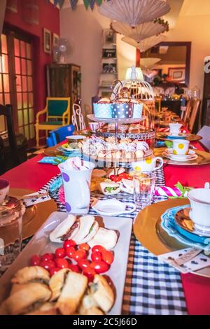 Thé coloré avec table, tasses à thé et soucoupes de fantaisie, avec des aliments sucrés et salés sur des plateaux Banque D'Images