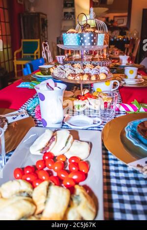 Thé coloré avec table, tasses à thé et soucoupes de fantaisie, avec des aliments sucrés et salés sur des plateaux Banque D'Images