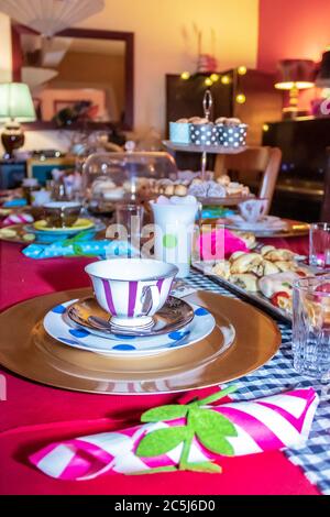 Thé coloré avec table, tasses à thé et soucoupes de fantaisie, avec des aliments sucrés et salés sur des plateaux Banque D'Images