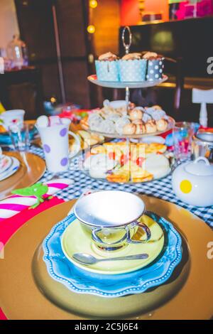 Thé coloré avec table, tasses à thé et soucoupes de fantaisie, avec des aliments sucrés et salés sur des plateaux Banque D'Images