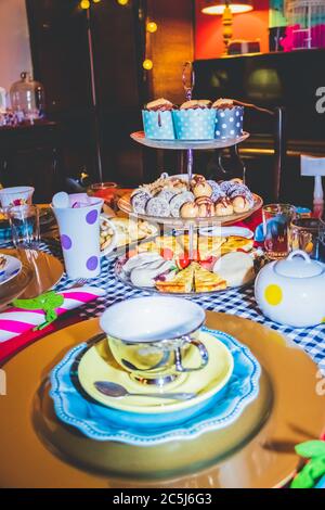 Thé coloré avec table, tasses à thé et soucoupes de fantaisie, avec des aliments sucrés et salés sur des plateaux Banque D'Images