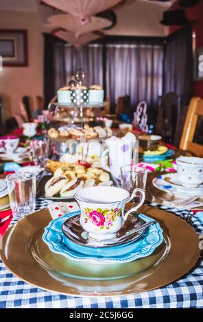 Thé coloré avec table, tasses à thé et soucoupes de fantaisie, avec des aliments sucrés et salés sur des plateaux Banque D'Images