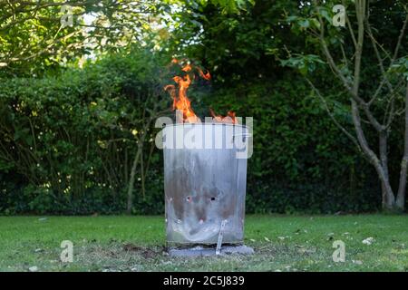 Près d'un incinérateur de jardin en métal fait maison vu brûler l'eau non toxique de ménage général dans un cadre de jardin. Banque D'Images