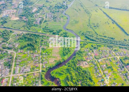 Vue aérienne paysage de petite rivière sinueuse entre la petite ville gare et le pont, ruisseau dans le champ vert, vue de dessus pré Banque D'Images