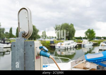 Prise électrique étanche connectée à un câble alimenté dans une marina de plaisance. Banque D'Images